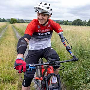 Das Bild zeigt einen Mann mit Armprothese, der Fahrrad fährt.